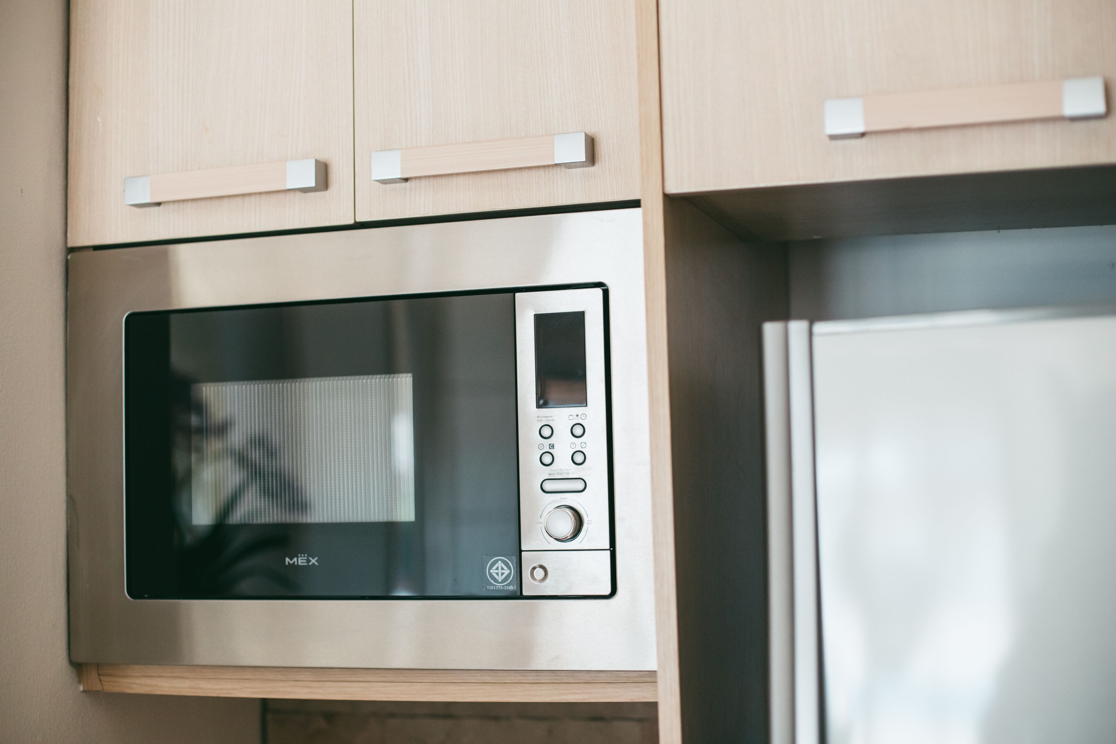 A modern kitchen with a built-in microwave and a stainless steel refrigerator.