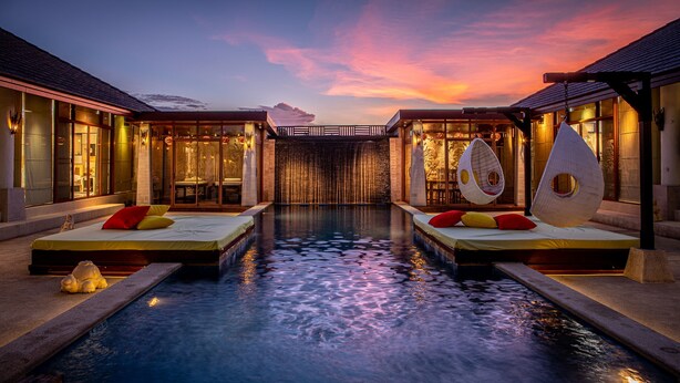 A luxurious hotel with a central pool, two guest rooms with beds and pillows, and a view of the sunset. - Dhevan Dara Resort & Spa (Hua Hin)
