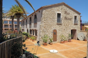 A stone building with balconies and potted plants. - Hotel San Carlos (Roses)