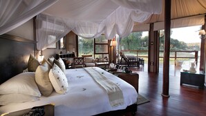 A spacious bedroom with a large bed, a desk, and a chair, all under a canopy. - Hamiltons Tented Camp (Bushbuckridge)