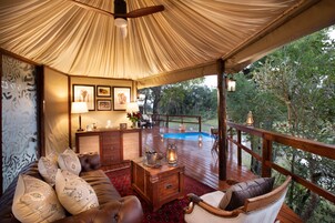 Una habitación acogedora y luminosa con terraza de madera, piscina y vistas a los árboles circundantes.