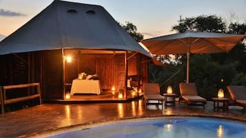 Una piscina al aire libre, sombrillas, sillones reclinables de piscina