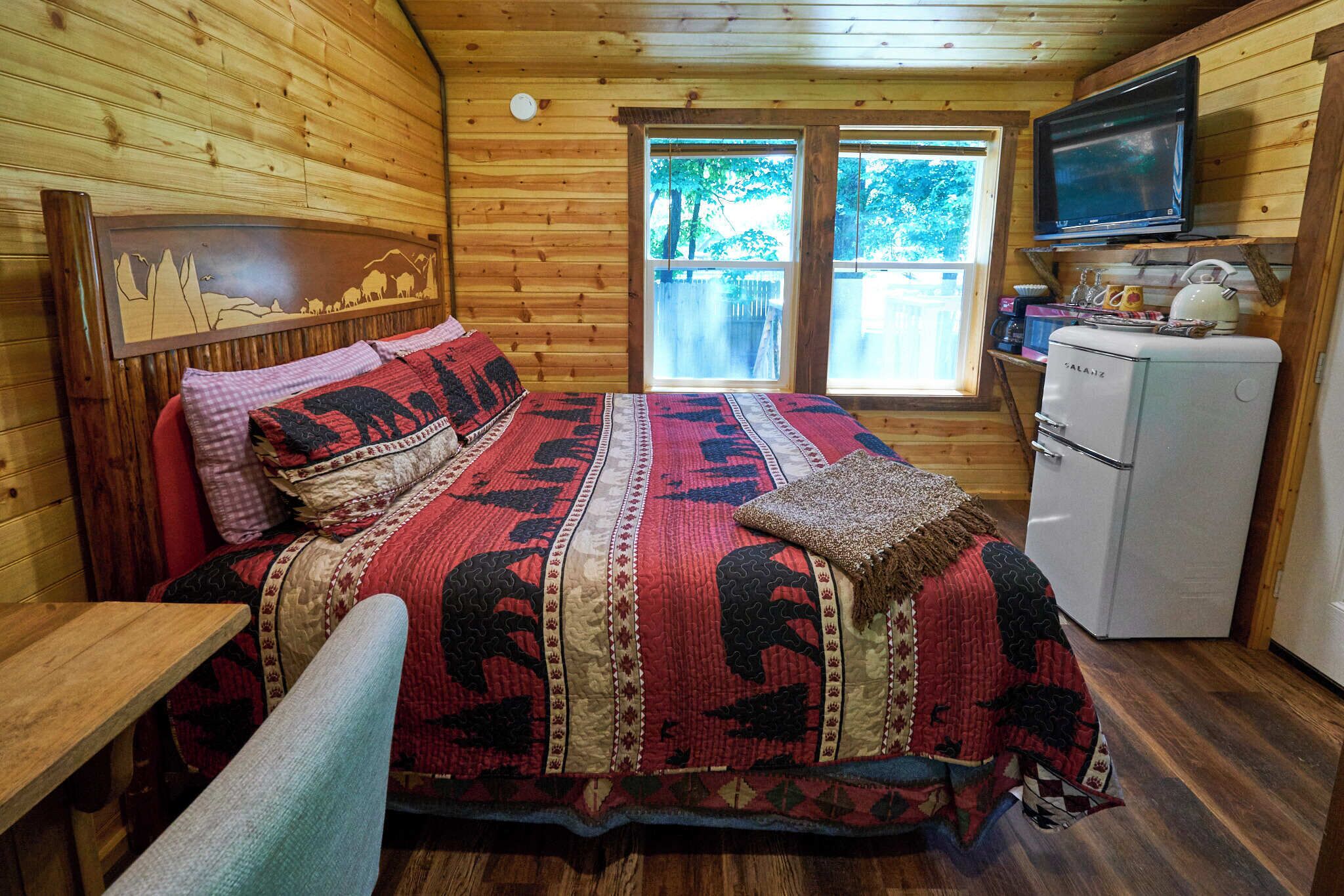 Accogliente camera con un letto, una televisione e un frigorifero.