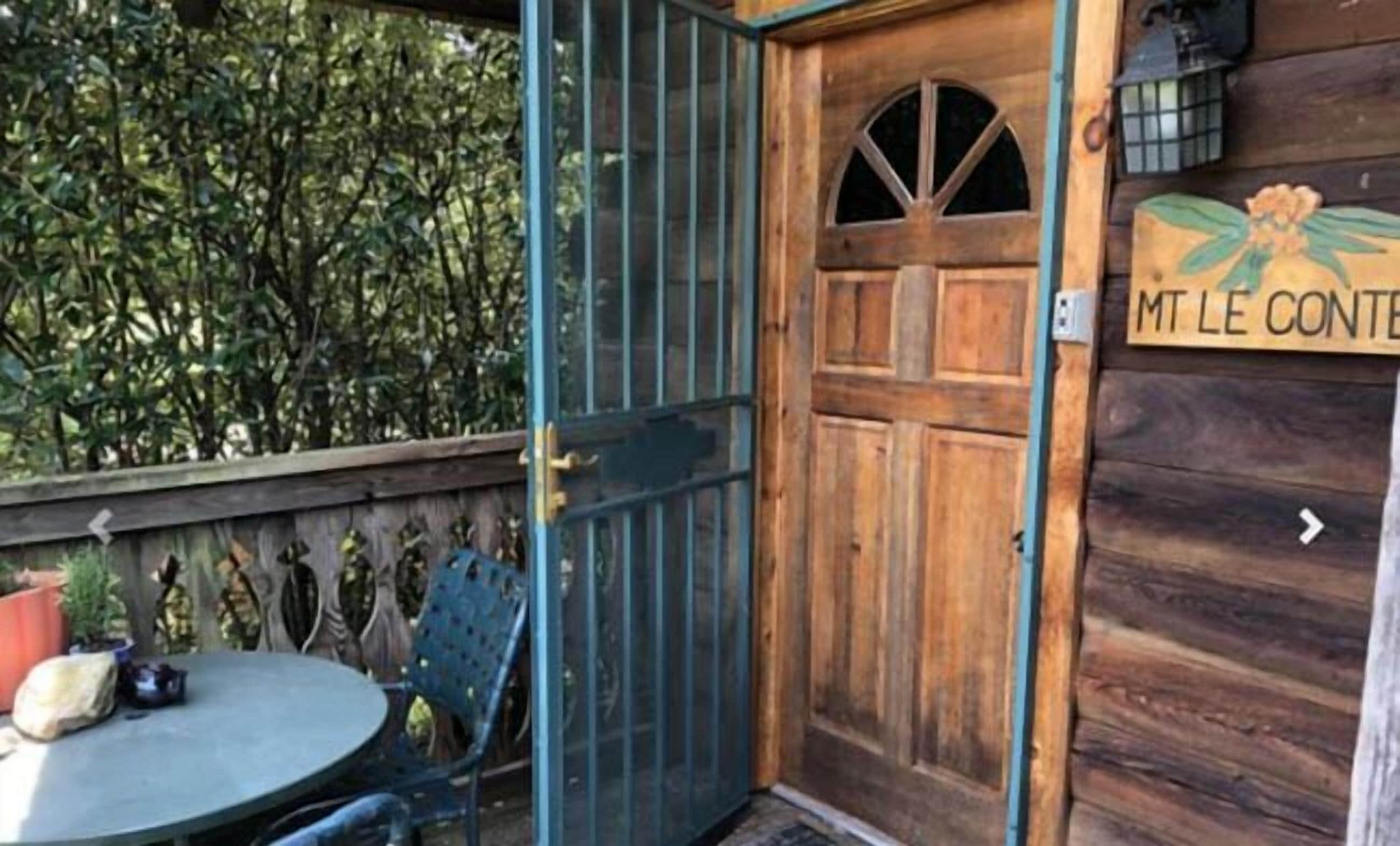 A wooden door with a metal gate, a small table with chairs, and a sign with text.