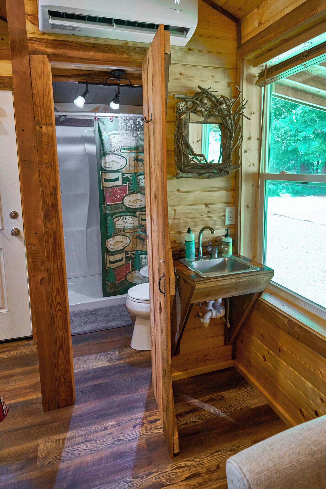Un baño de cabaña de madera con lavamanos, inodoro y ducha.