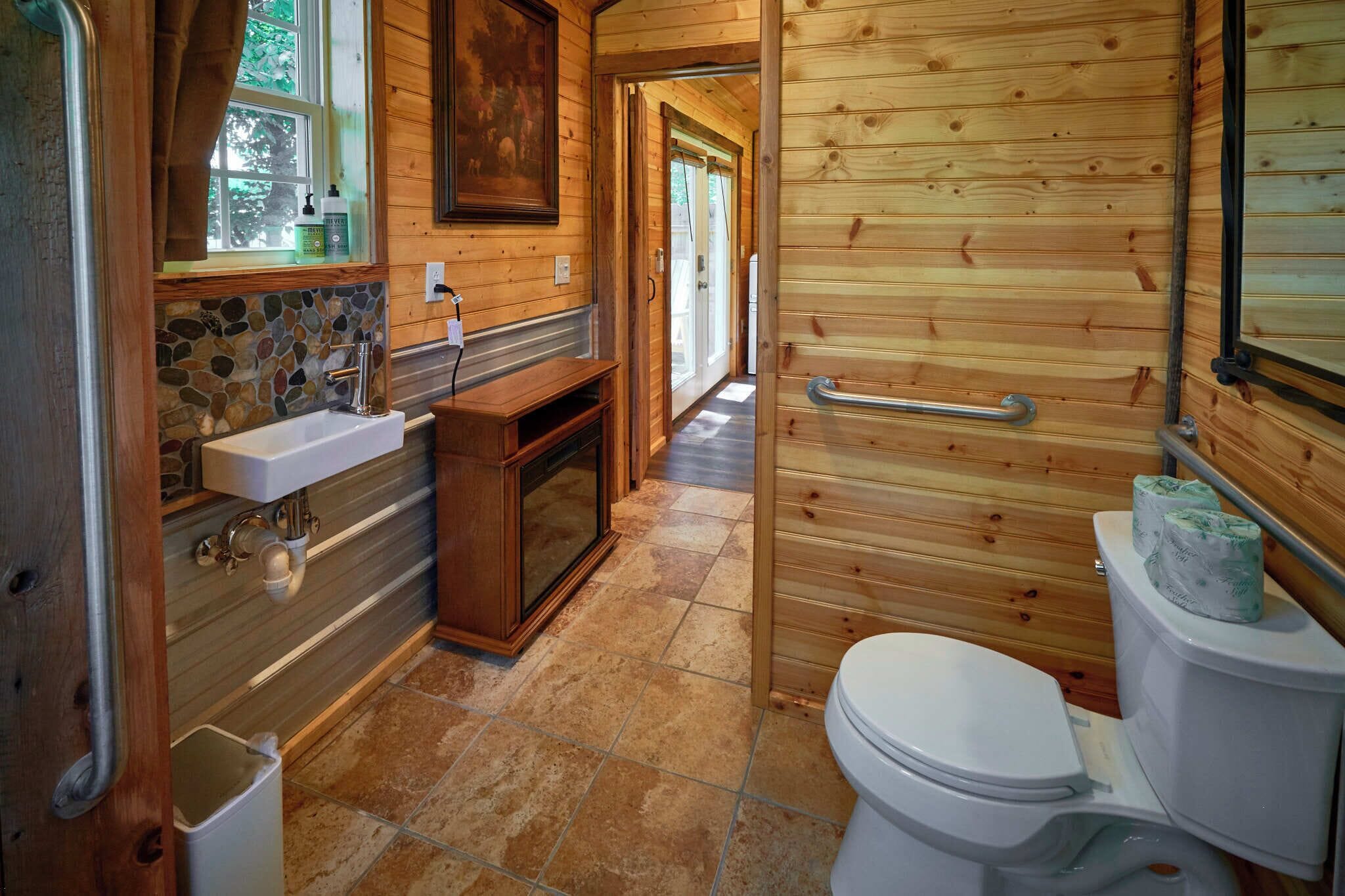 A wooden interior with a bathroom featuring a sink, toilet, and a shower area.