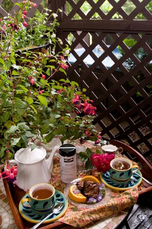Un plateau avec une théière, des tasses, un thermos et une assiette contenant de la nourriture et des fleurs.