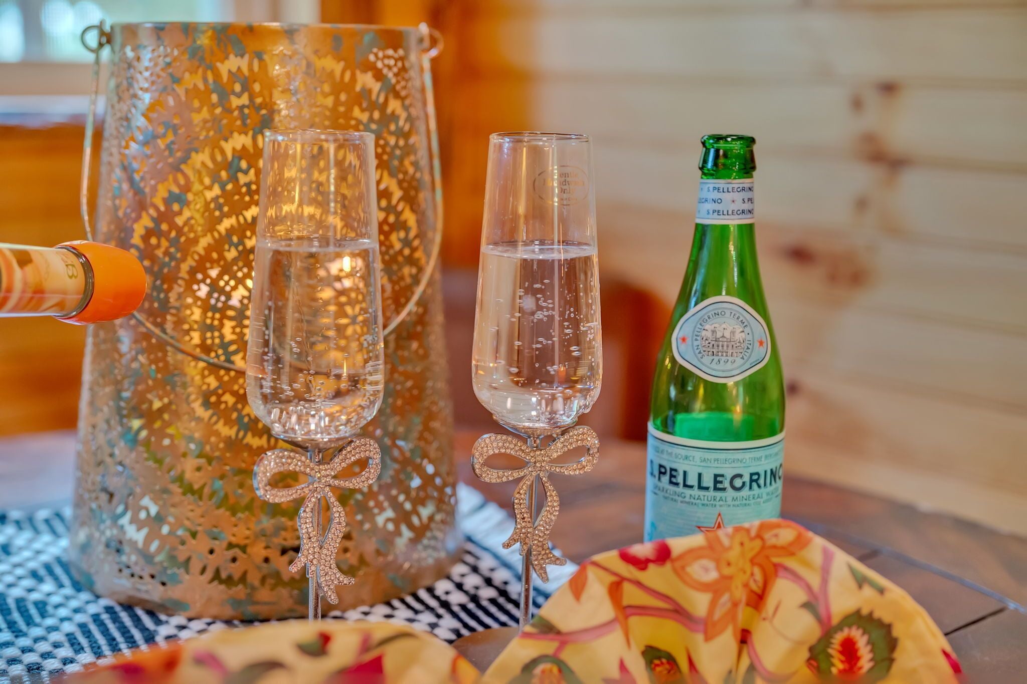 Een fles San Pellegrino bruiswater, twee glazen en een decoratieve karaf op een tafel.