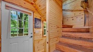 A wooden cabin interior with a white door, a small window, and a sign that reads "WITH you I am home." - Creekwalk Inn and Cabins (Cosby)