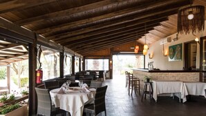 An indoor dining area with wooden beams, wicker chairs, and tables set for dining. - Happy Village & Camping (Rome)