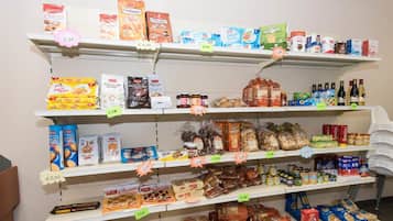 Uno scaffale di un negozio di alimentari pieno di diversi prodotti alimentari e bevande, tra cui snack, pane e latticini.
