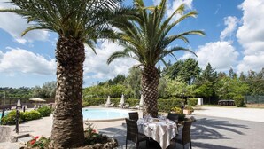 A poolside area with two palm trees, a dining table with chairs, and a clear blue sky. - Happy Village & Camping (Rome)
