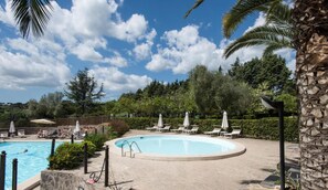 Piscine extérieure en saison, parasols, chaises longues