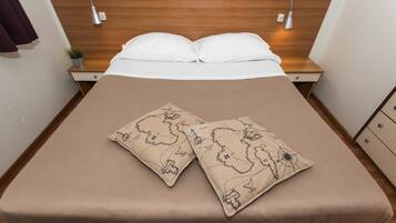 A neatly made bed with white pillows and two decorative pillows featuring a map design.