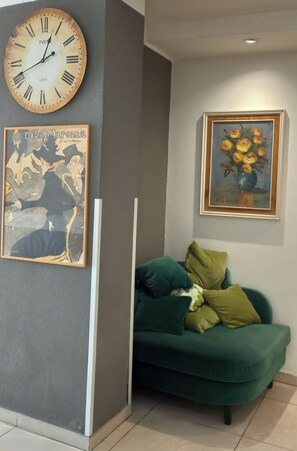 Experience the essence of Paris in this stylish room, featuring a vintage clock, elegant artwork, and plush sofa.