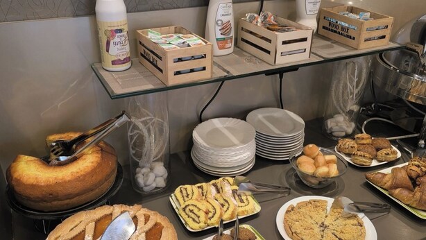 Een buffet met verschillende gebakken producten, waaronder taarten, koekjes en gebak, evenals sauzen en drankjes.
