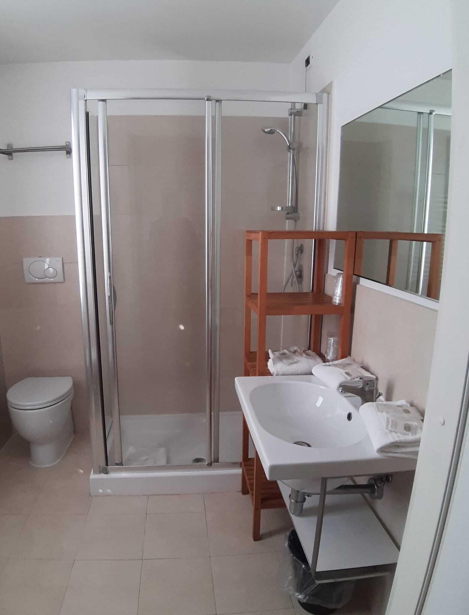 A modern bathroom with a glass-enclosed shower, a white sink, and a toilet.