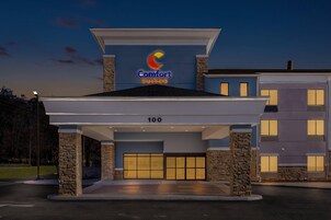 A hotel entrance with a sign for Comfort Suites, a covered driveway, and a stone facade.