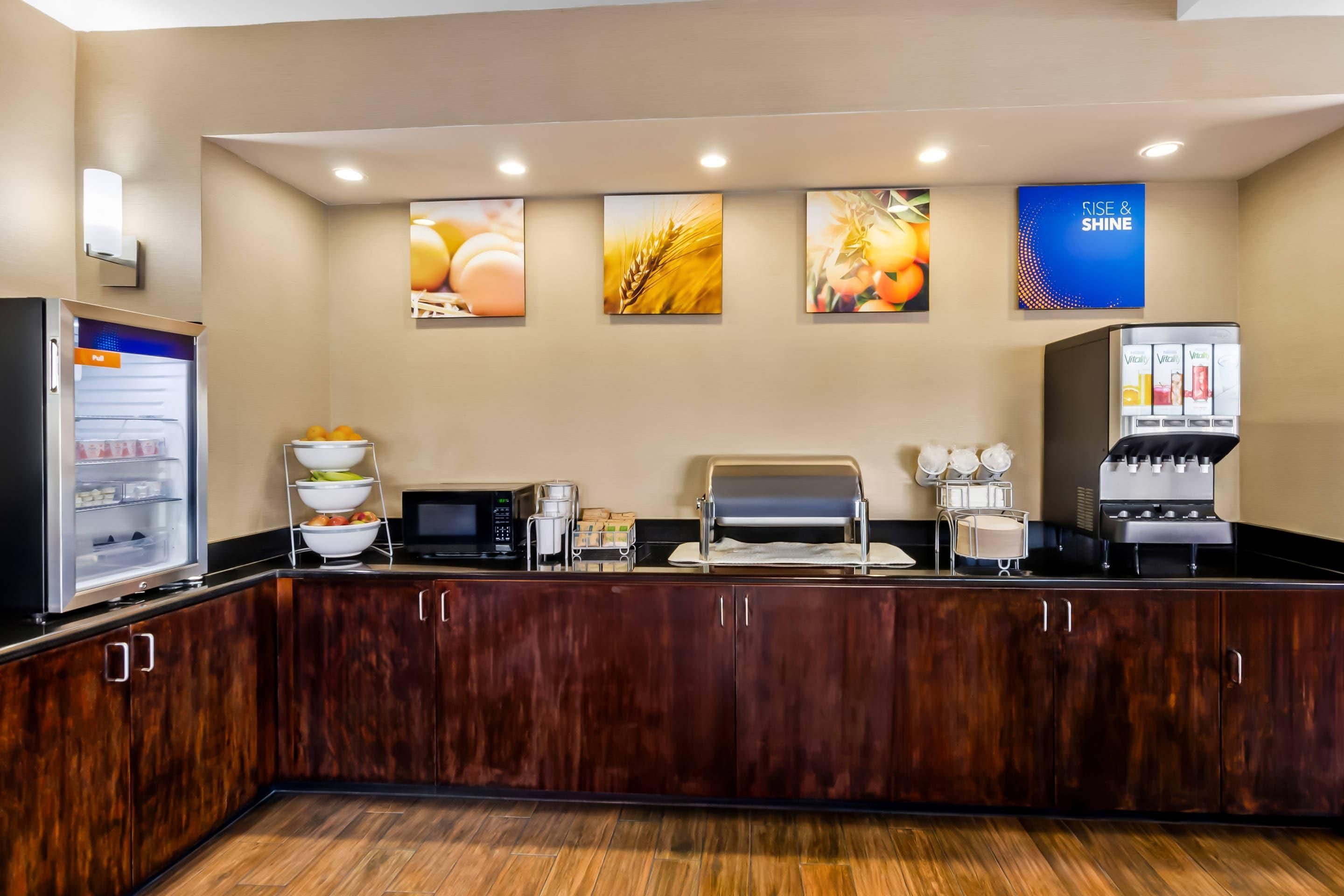 A self-service breakfast area with a refrigerator, microwave, and coffee machine.