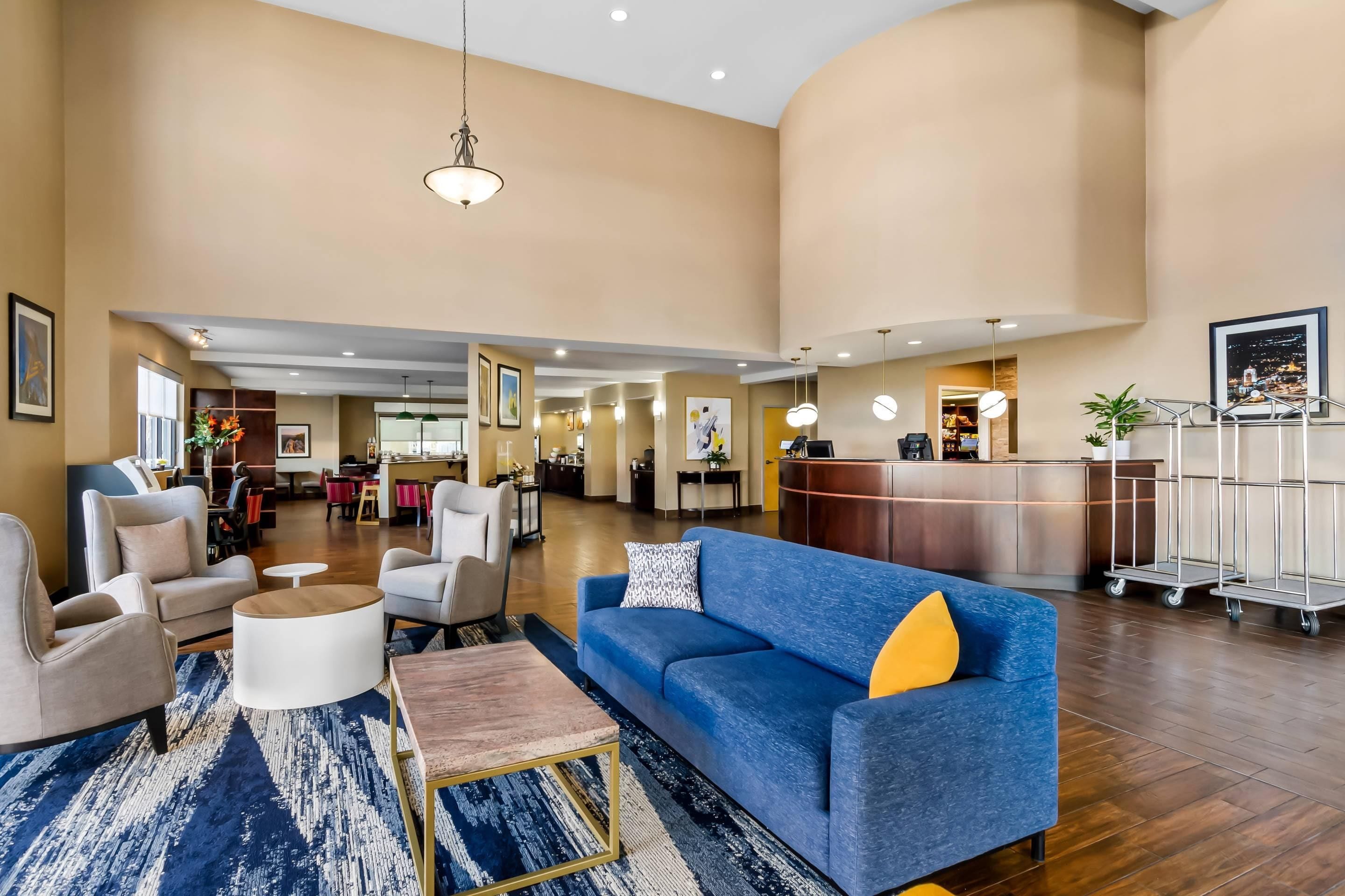 A spacious lobby with a blue sofa, a reception desk, and a dining area.