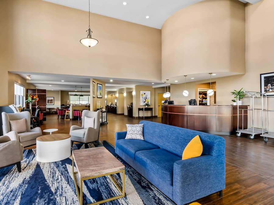 Un vestíbulo amplio con un sofá azul, un mostrador de recepción y una zona de comedor.