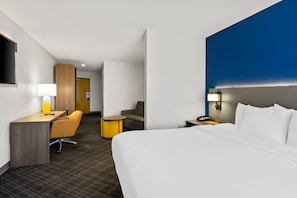 Una habitación de hotel con cama, escritorio, silla y una pequeña mesa.