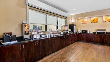 A breakfast bar with waffle and coffee machines, a large window, and a kitchen area with a microwave and toaster.