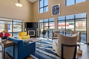 A spacious living area with a fireplace, comfortable seating, and large windows offering views of the outside.