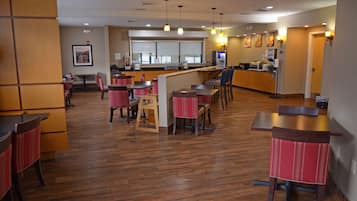 Un restaurante con piso de madera, sillas rojas y marrones, y una barra con un menú a la vista.