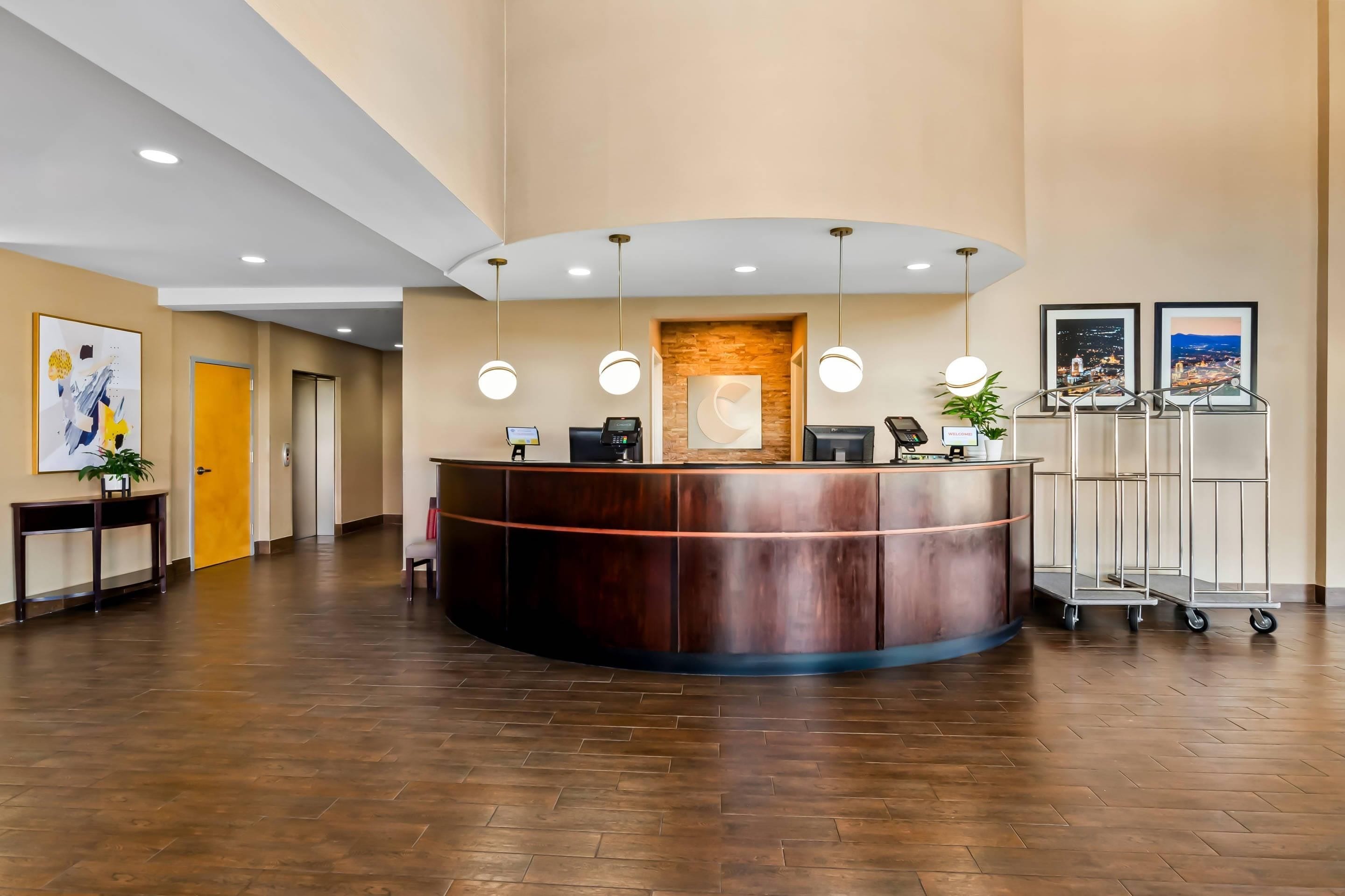 A hotel reception area with a curved reception desk, a digital check-in station, a reception counter, and a wall-mounted welcome sign.