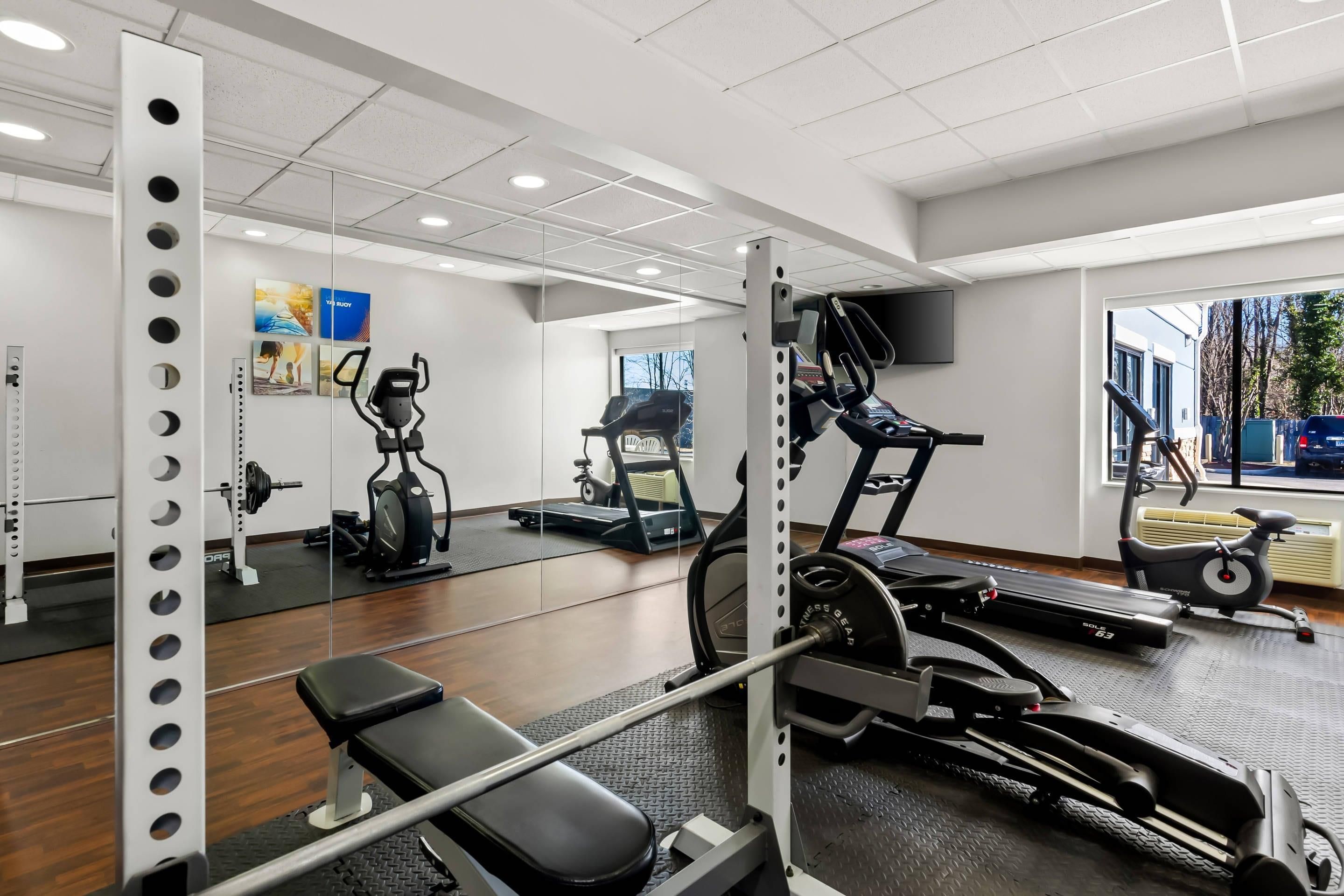 A gym with exercise equipment, a bench, and a mirrored wall.