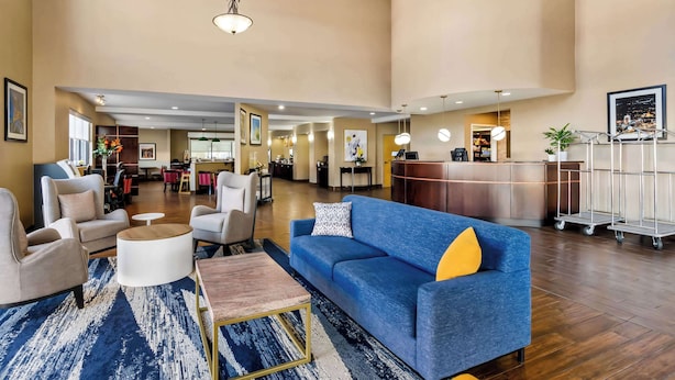 Eine großzügige Lobby mit einem blauen Sofa, weißen Sessel und einer Rezeption.