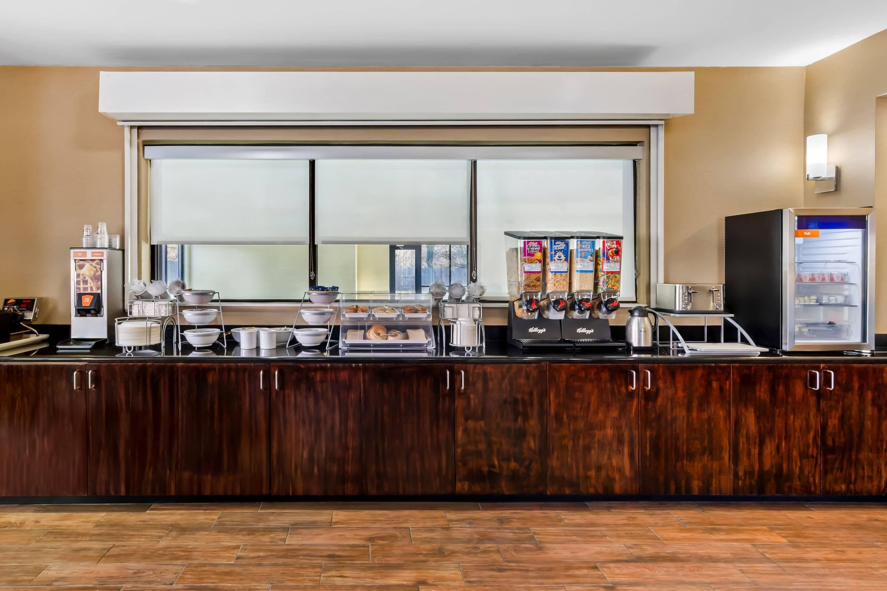 A self-service breakfast bar with various food items and a coffee machine.