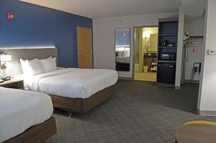 Habitación de hotel con dos camas, baño y kitchenette.