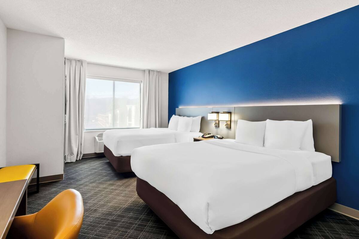 Een hotelkamer met twee bedden, een bureau en een stoel.