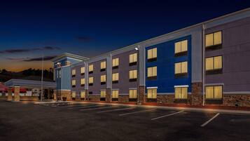 A multi-story hotel with a flat facade, large windows, and a parking lot in front.