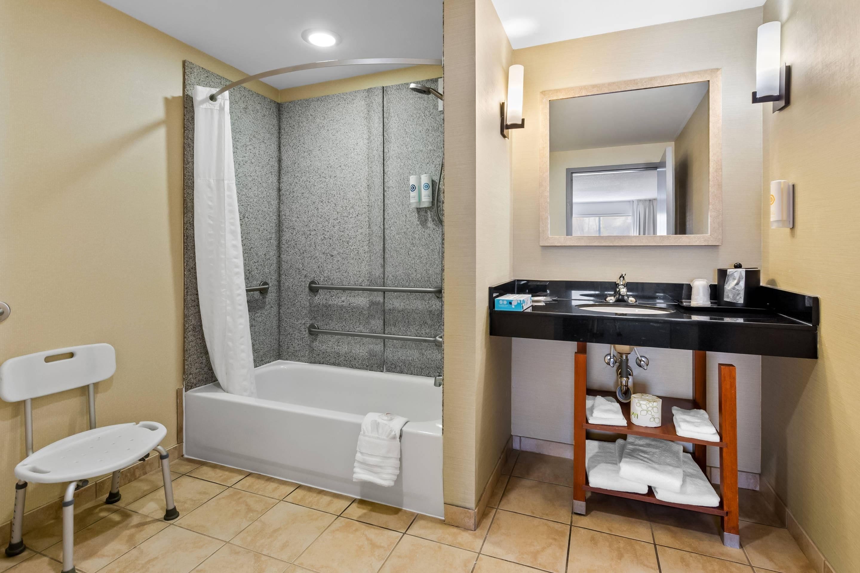 A bathroom with a shower, a toilet, a sink, and a mirror.