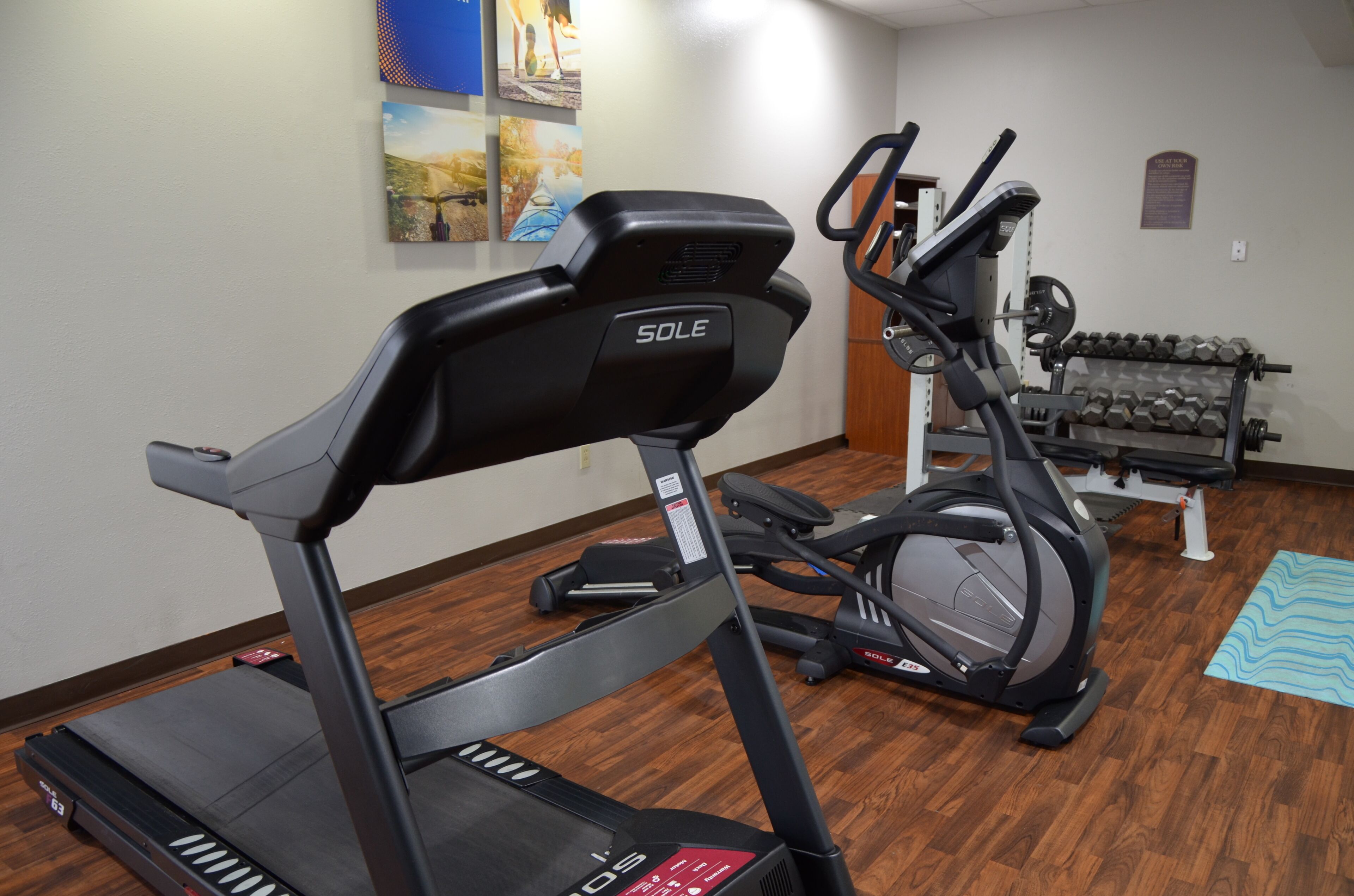 Un gimnasio en casa con cinta de correr, elíptica y mancuernas.
