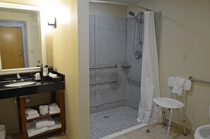 Een badkamer met een wastafel, spiegel, douche en toilet.