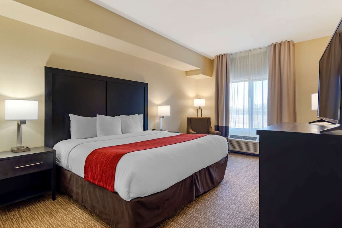 A hotel room with a large bed, bedside lamps, a desk, and a TV.