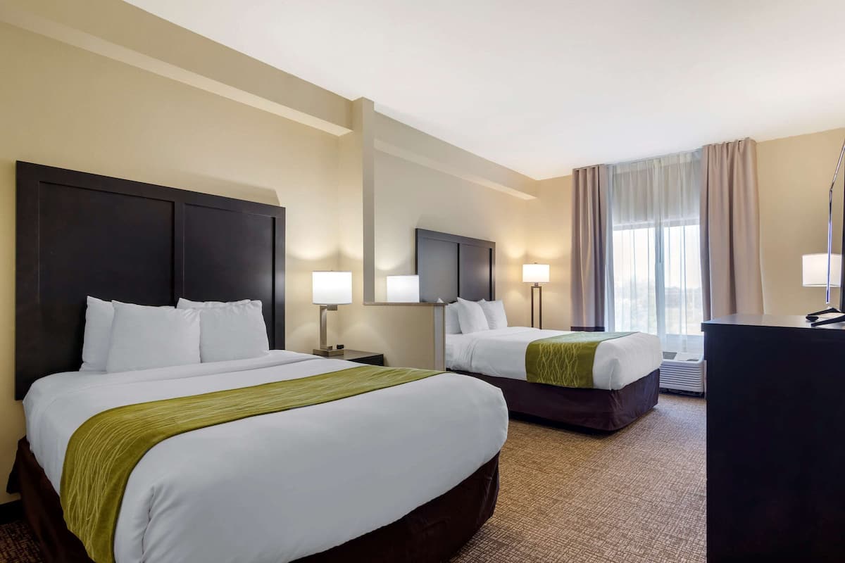 A hotel room with two beds, a desk, and a large mirror.