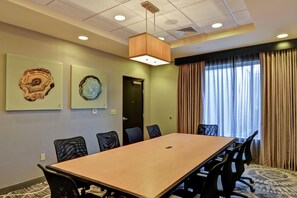 A conference room with a long table, chairs, a ceiling light, and two wall-mounted artworks. - DoubleTree by Hilton Hotel Baton Rouge (Baton Rouge)