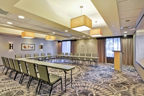 Une salle de conférence avec une longue table et des chaises, un éclairage au plafond et un tapis à motifs.