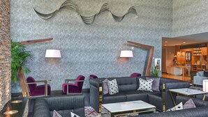 A modern lounge area with grey sofas, red chairs, and a bar area with a visible counter.