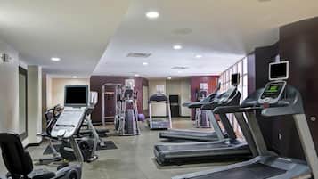 Un gimnasio con cintas de correr, elípticas y equipo de pesas.