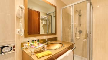 A bathroom with a sink, mirror, hair dryer, and shower.