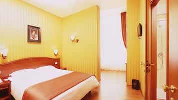 Habitación de hotel con cama, lámparas de noche, un cuadro en la pared y una puerta a la derecha.
