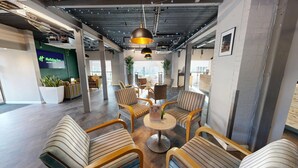 Un espacio lounge moderno con sillas a rayas, una mesa redonda y lámparas colgantes.