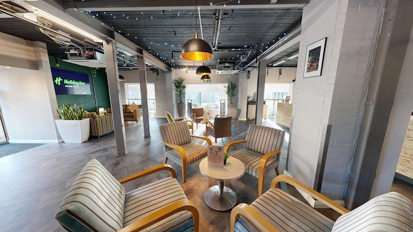 A modern lounge area with striped chairs, a round table, and hanging pendant lights. - Holiday Inn Kenilworth - Warwick by IHG (Kenilworth)