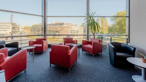 A modern indoor seating area with red and black chairs, a small table, and a potted plant.